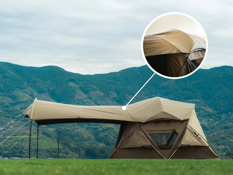 山々を背景にした広々とした草原に、カーキ色の大型テントとタープ