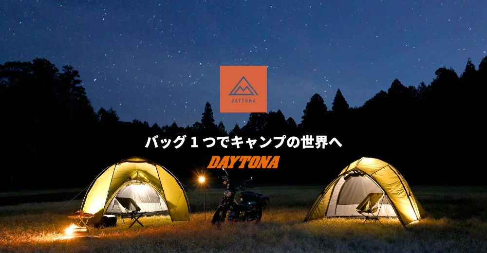 星が輝く夜空の下、草原に2つのテントとバイクが並び、焚き火の光が暖かく灯るキャンプシーンです。「バッグ1つでキャンプの世界へ」というメッセージが添えられ、デイトナのロゴも配置されています。