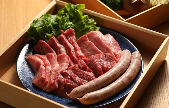 木製のお盆に盛られた、様々な種類の生肉とソーセージ、そして新鮮なレタスの盛り合わせ