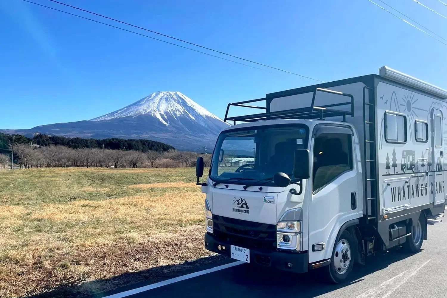 雪を冠した富士山を背景に停車するキャンピングカー