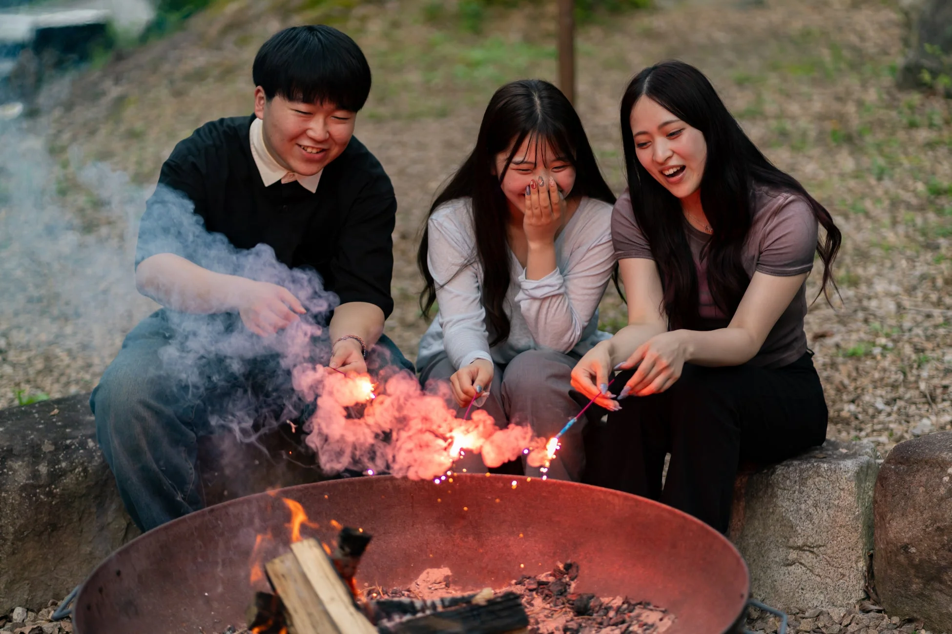 焚き火台を囲んで花火を楽しむ若者たち