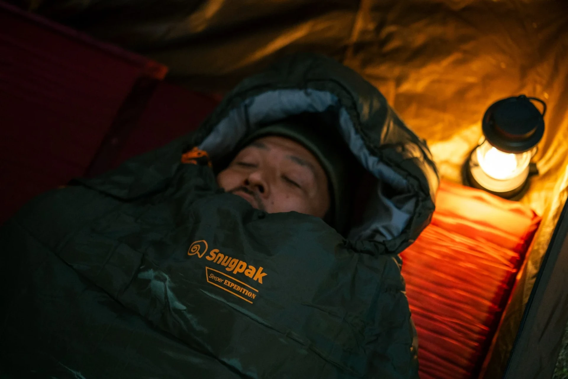 テントの中で寝袋に入って眠る男性の様子