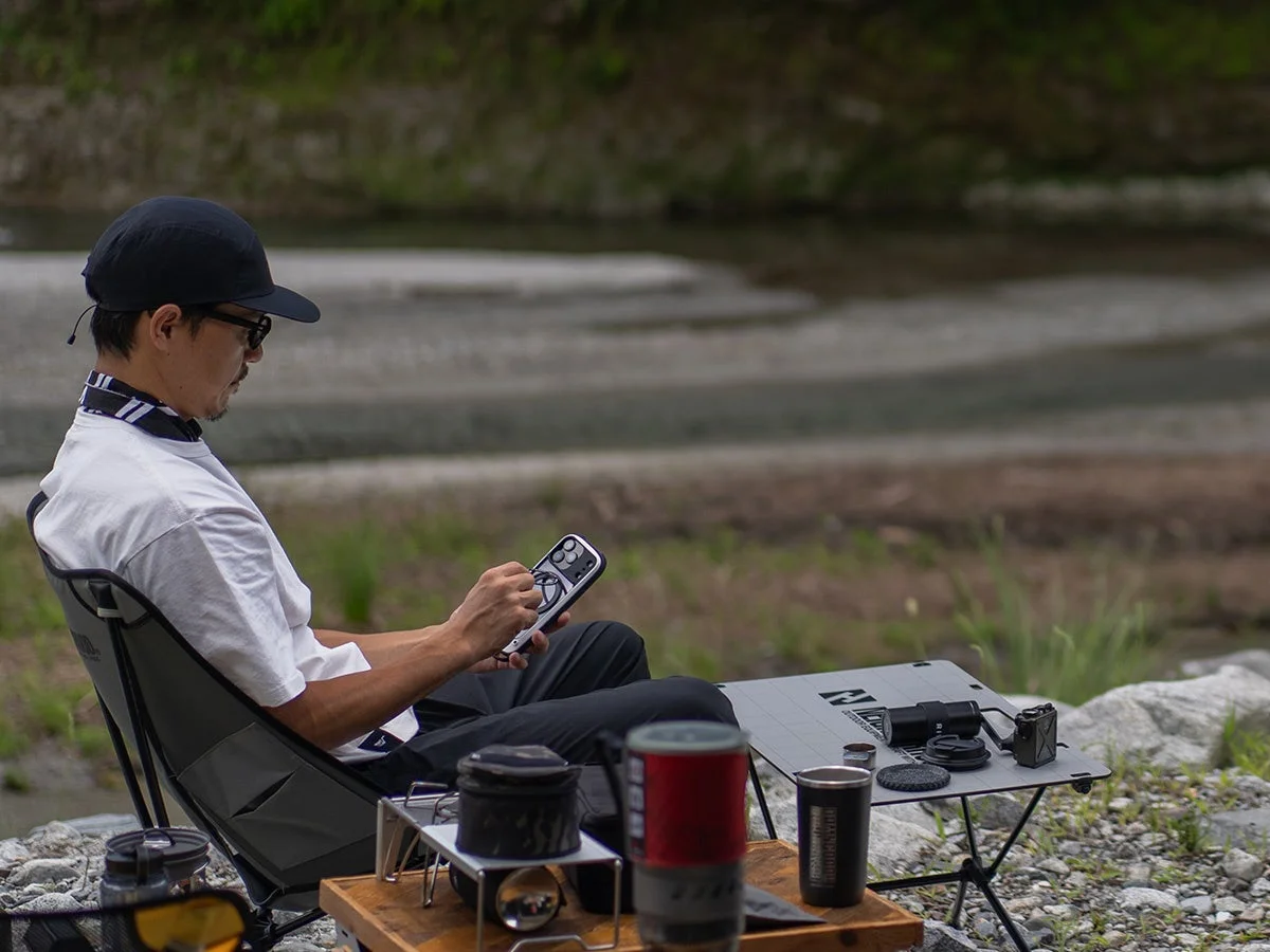 アウトドアでスマホを操作する男性とケース